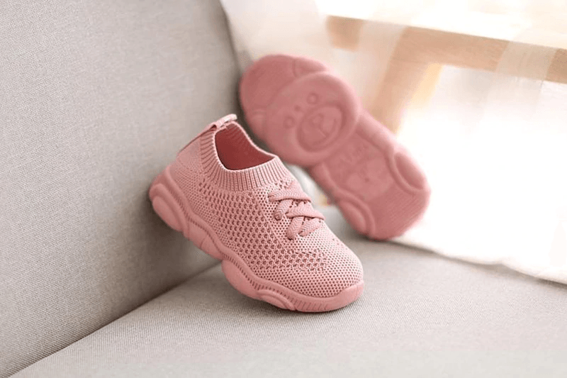 Pink baby sneakers with knit uppers and visible treaded outsole underside