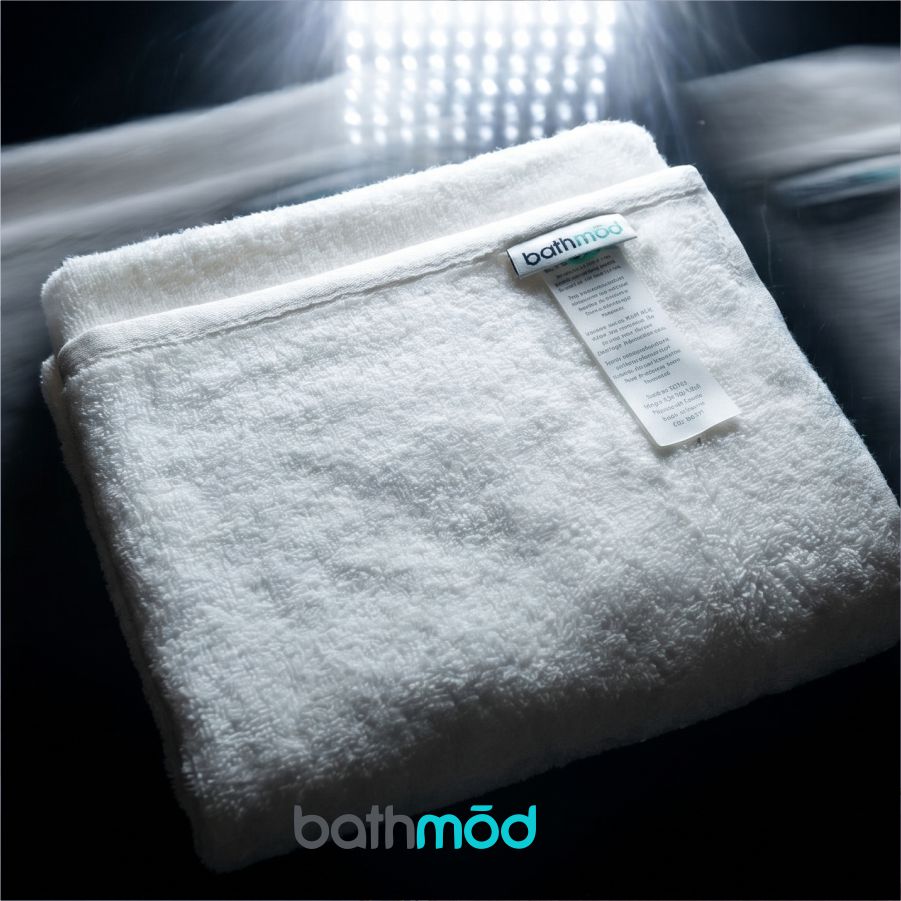Folded white organic bath mat with Bathmod tag