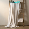 Two white bath sheets, one draped over a wooden stand with a folded towel