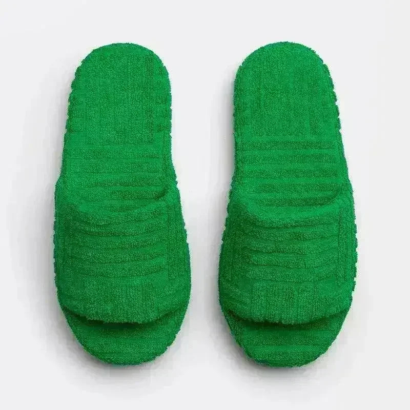 Pair of green fuzzy open-toe slide slippers with thick textured sole.