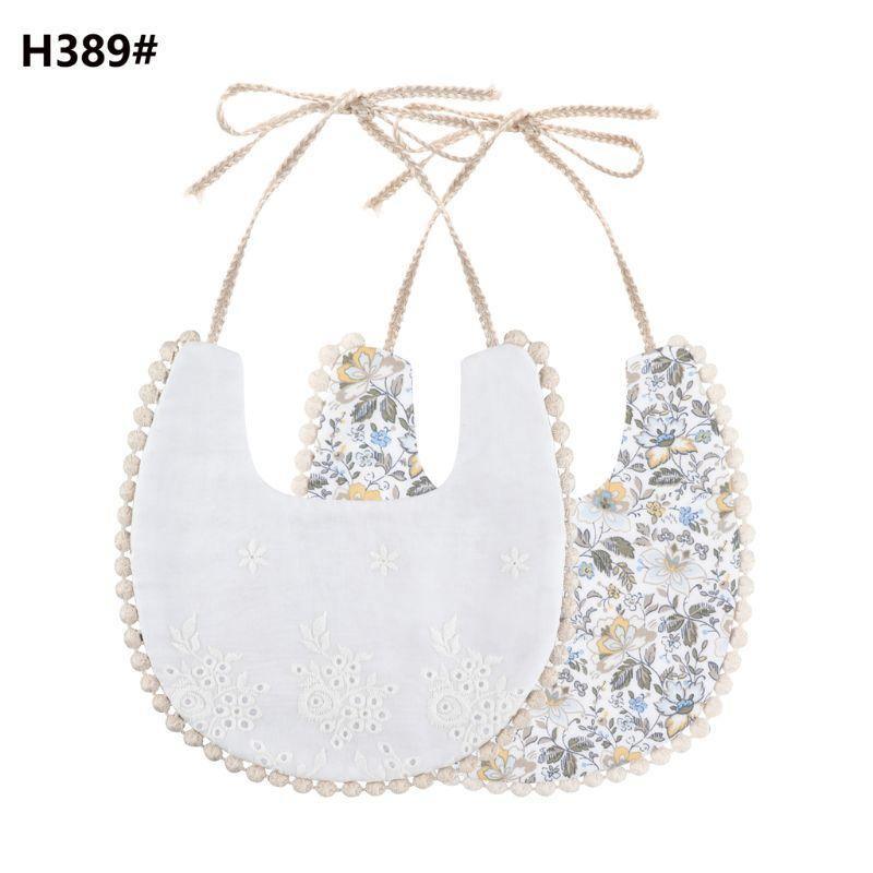 Double-sided cotton baby bib with tassel ties; white eyelet and floral print.