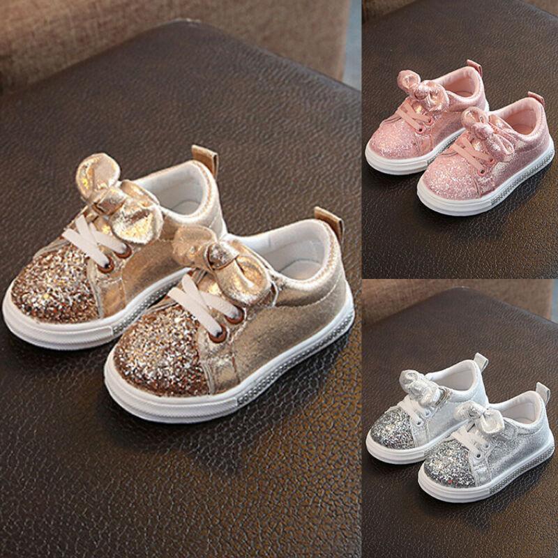 Toddler glitter sneakers with bow detail in gold and pink colorways, white soles.