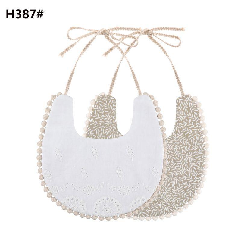 Infant double-sided bib with tassel ties, white eyelet front and beige patterned reverse