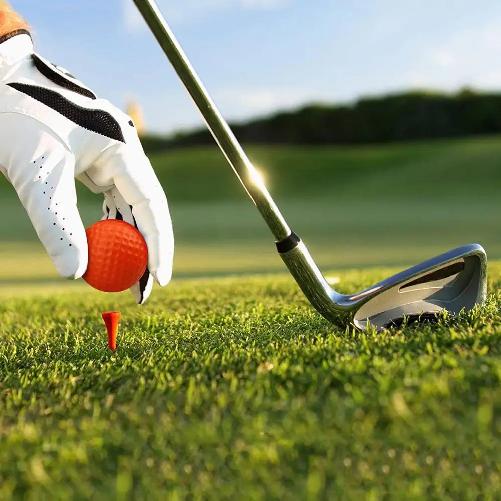 Orange foam golf practice ball on green tee, dimpled surface
