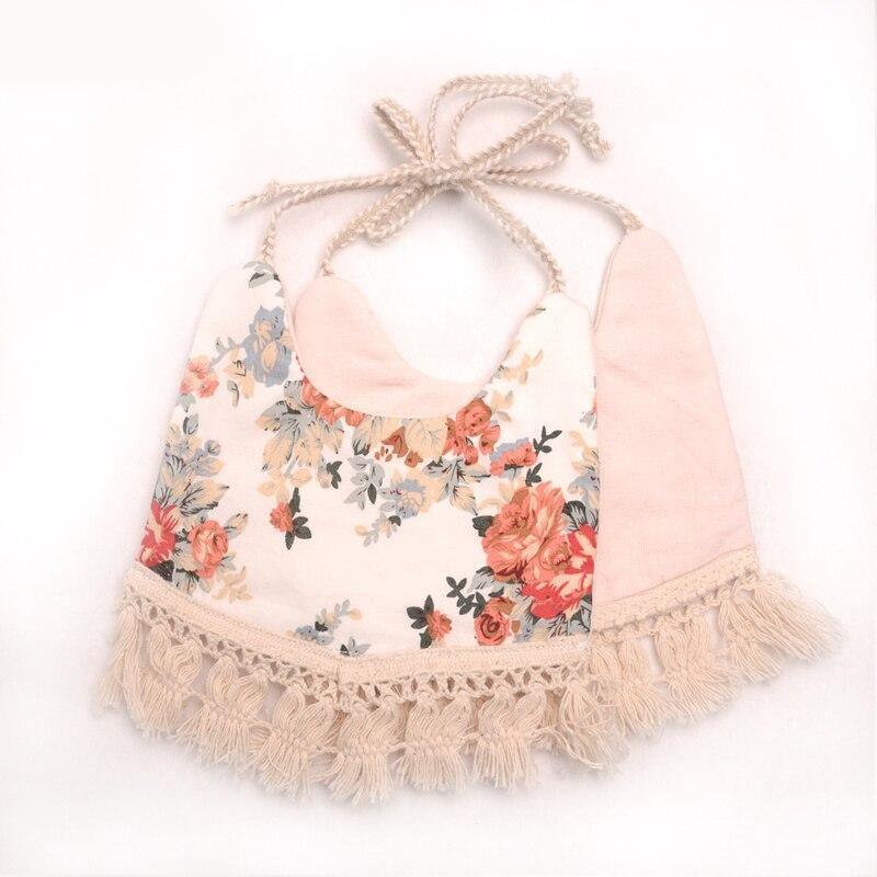Infant bib with floral print front and pink back panel, scalloped edge and fringe trim