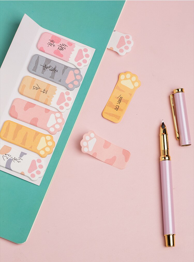 Cat paw sticky notes with pastel tab designs, shown with two pink and gold pens
