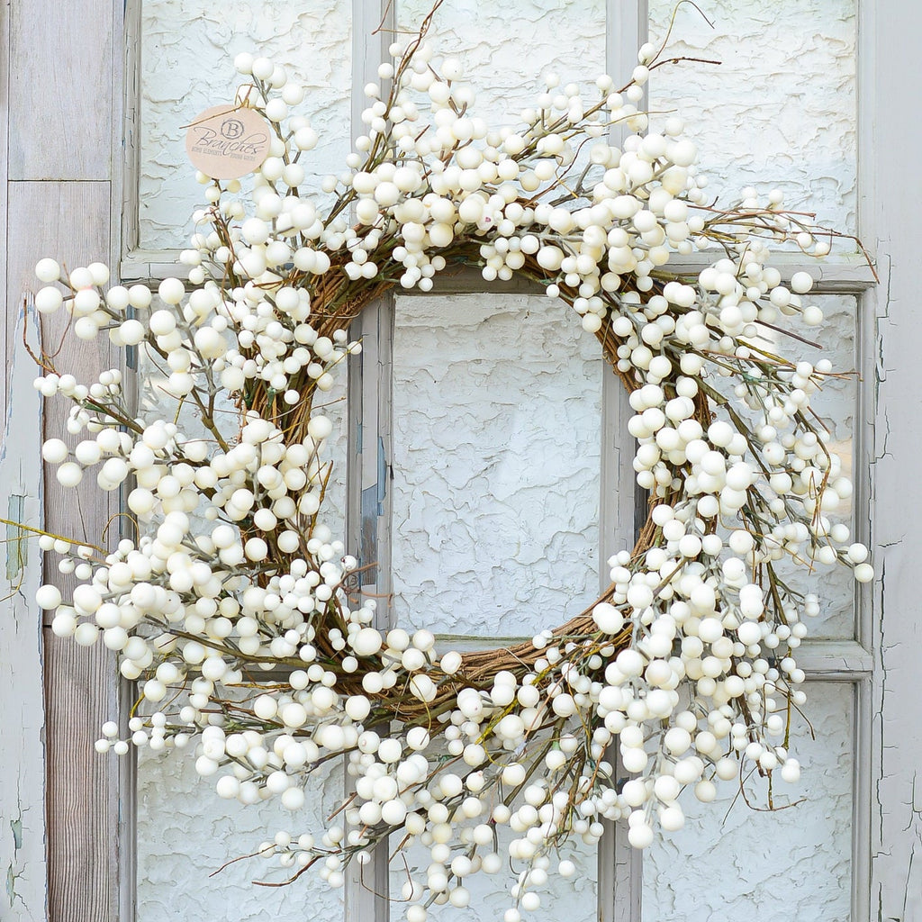 Cream berry wreath with full berry clusters on a circular twig base, hanging on a door