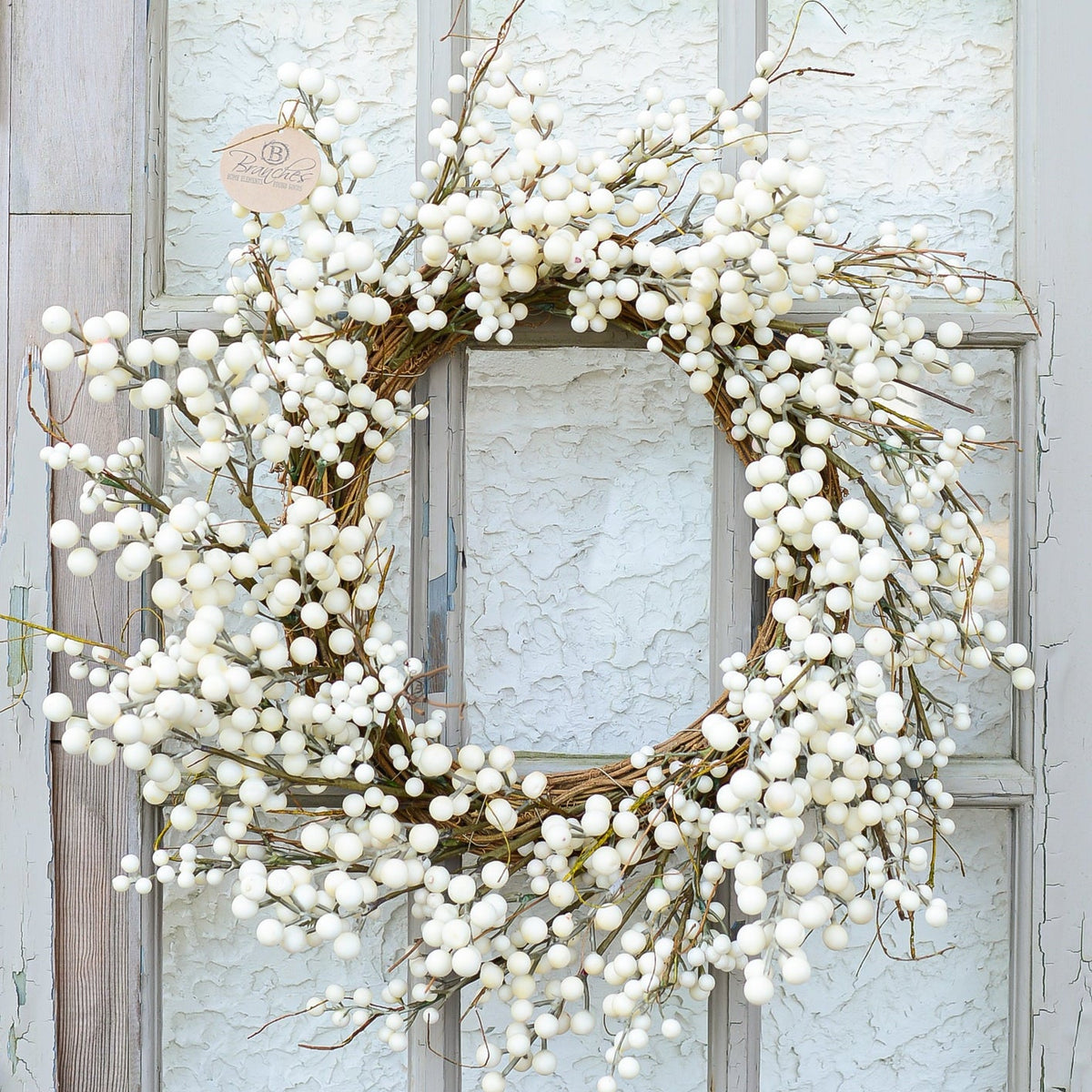 Cream berry wreath with full berry clusters on a circular twig base, hanging on a door