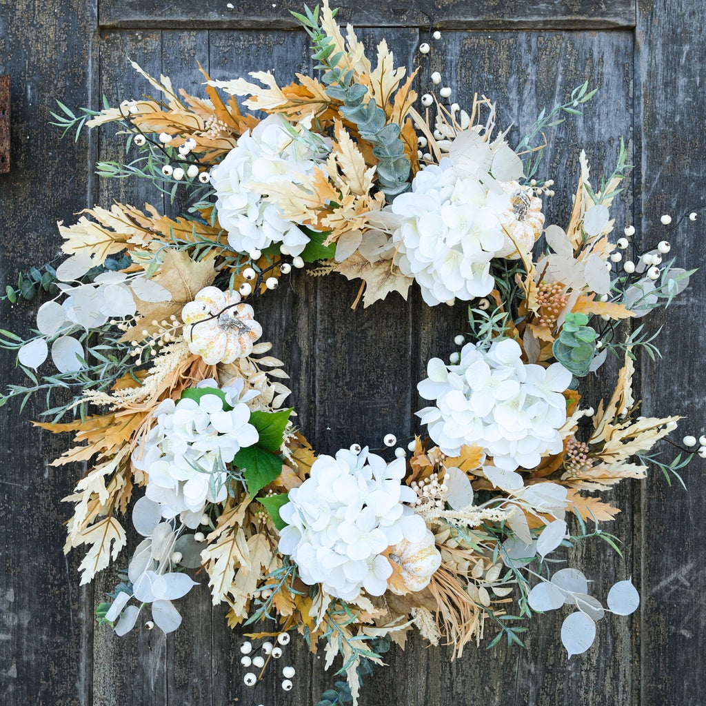 Truffle wreath with white hydrangea blossoms, dried tan leaves, and eucalyptus with berry details.