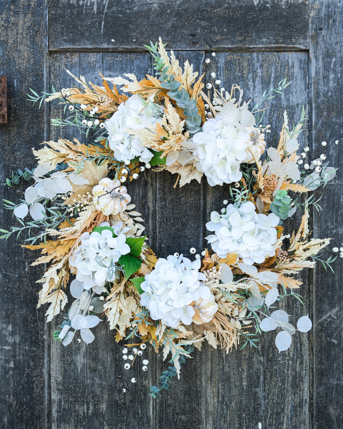 Truffle wreath centered on a round base, with white hydrangea clusters and tan leaf accents.