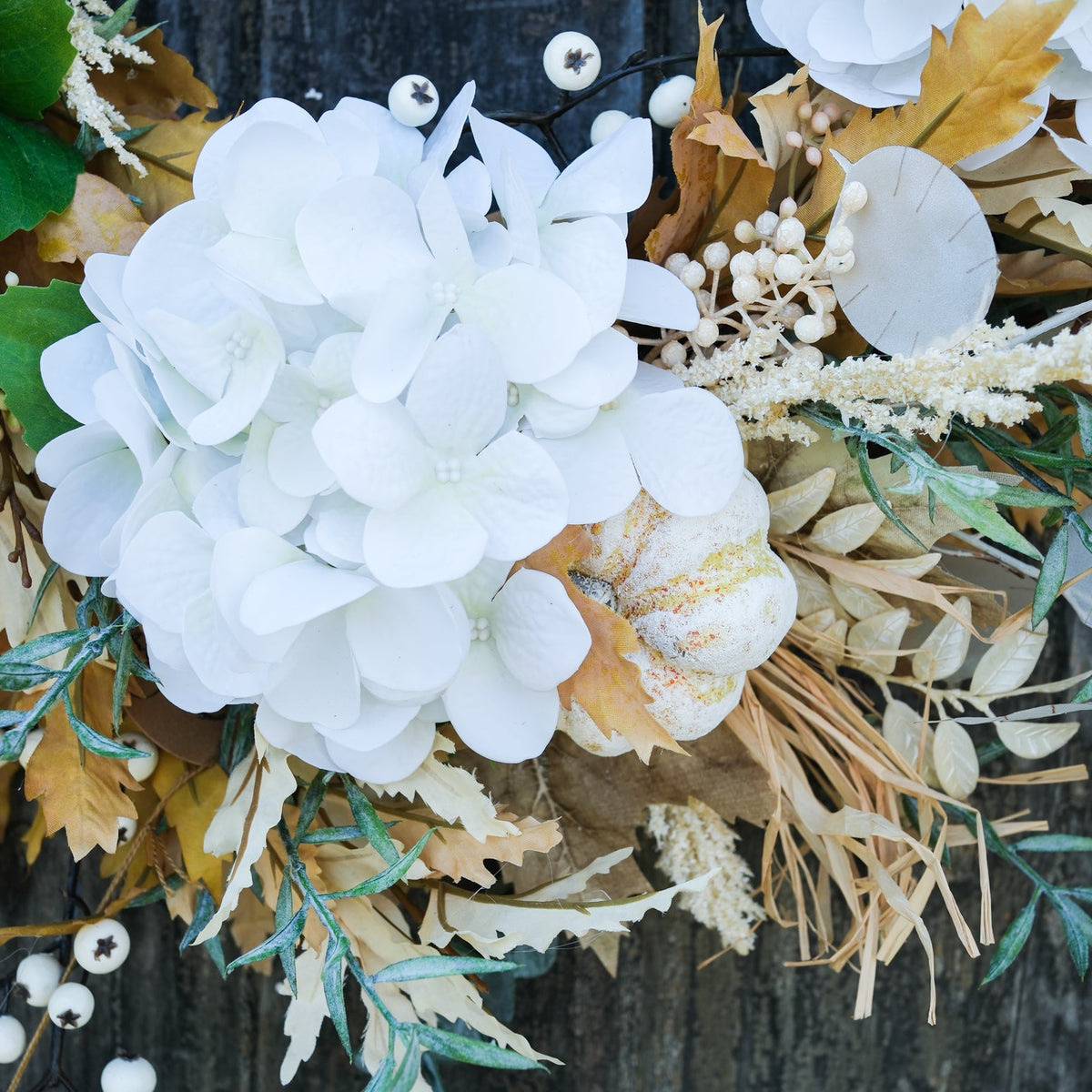 Truffle wreath close-up with white hydrangea petals, tan leaves, and eucalyptus sprigs with berries.