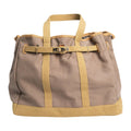 Tan canvas tote bag with tan straps, front buckle, and gold-tone hardware