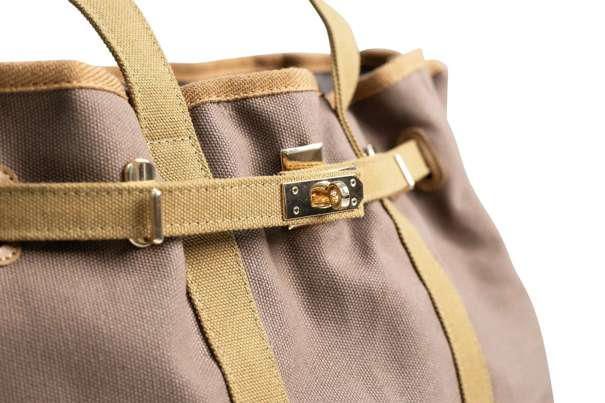 Tan canvas tote bag front buckle with gold-tone hardware and stitched strap