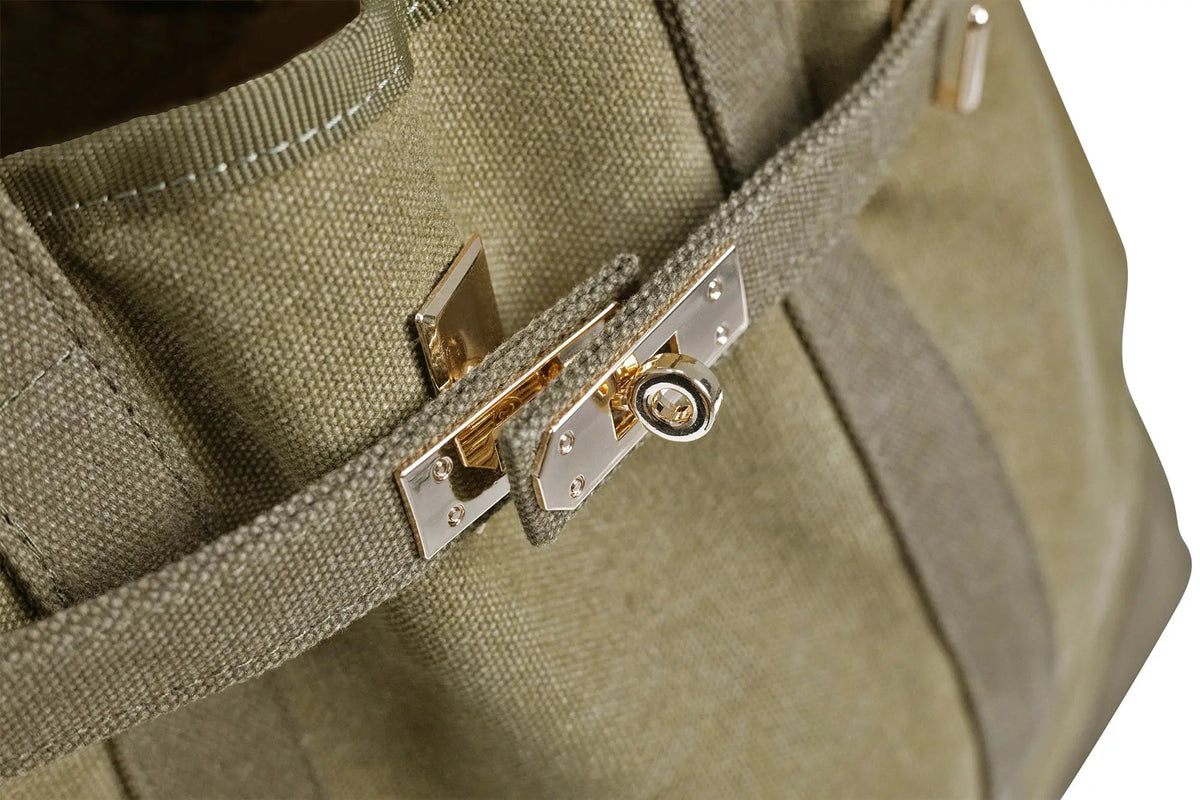Olive canvas tote bag close-up of front snap lock and gold-tone rivets