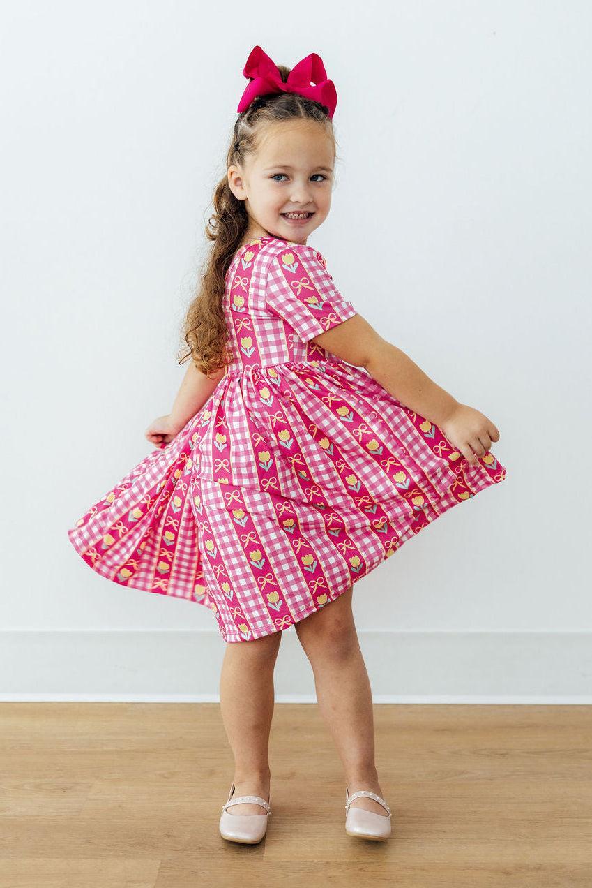 Girls pink plaid twirl dress with tulip and bow print, gathered waist and flared skirt