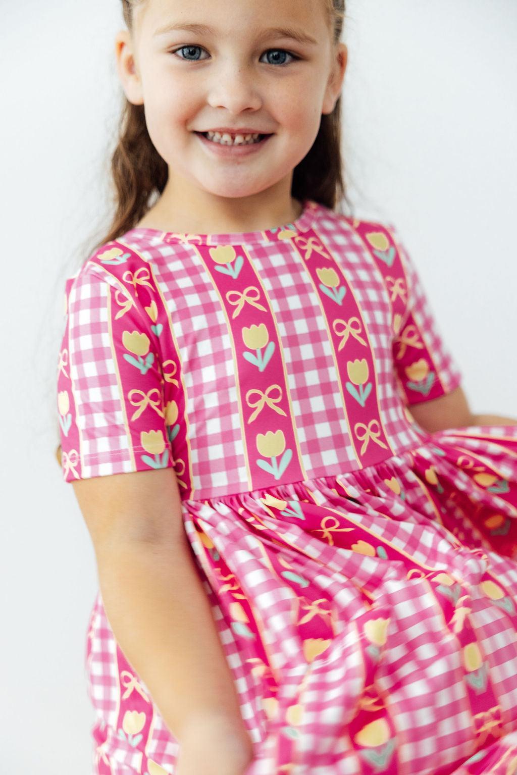 Girls pink plaid twirl dress with tulip and bow print, short sleeves and gathered skirt
