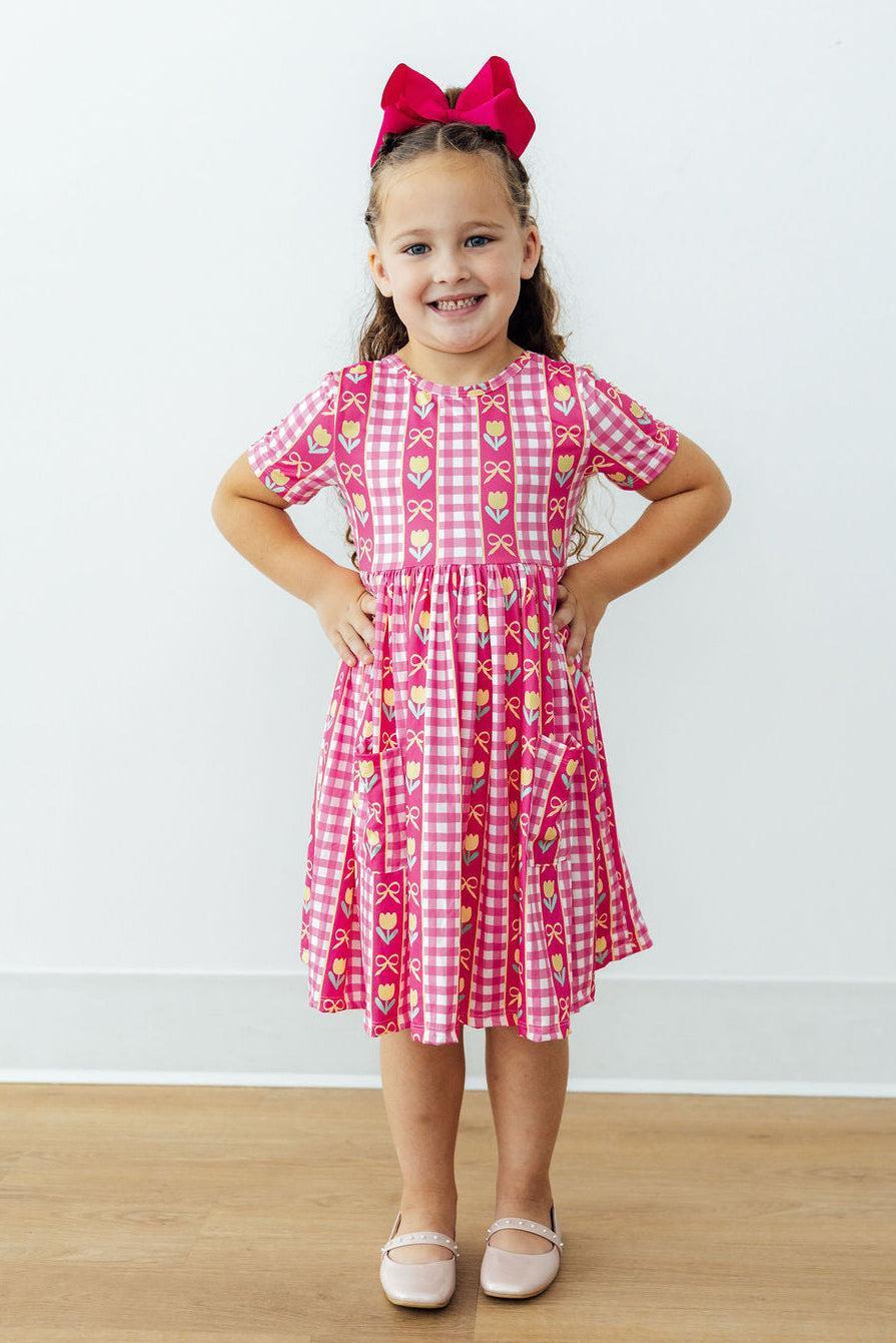 Girls pink plaid twirl dress with tulip and bow print, gathered waist and short sleeves