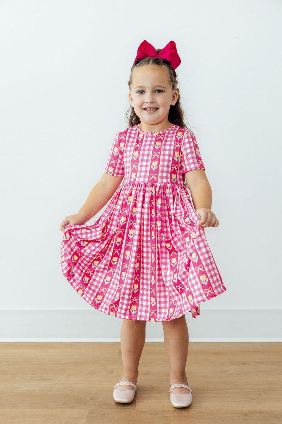 Girls pink plaid twirl dress with tulip and bow print, flared skirt and short sleeves