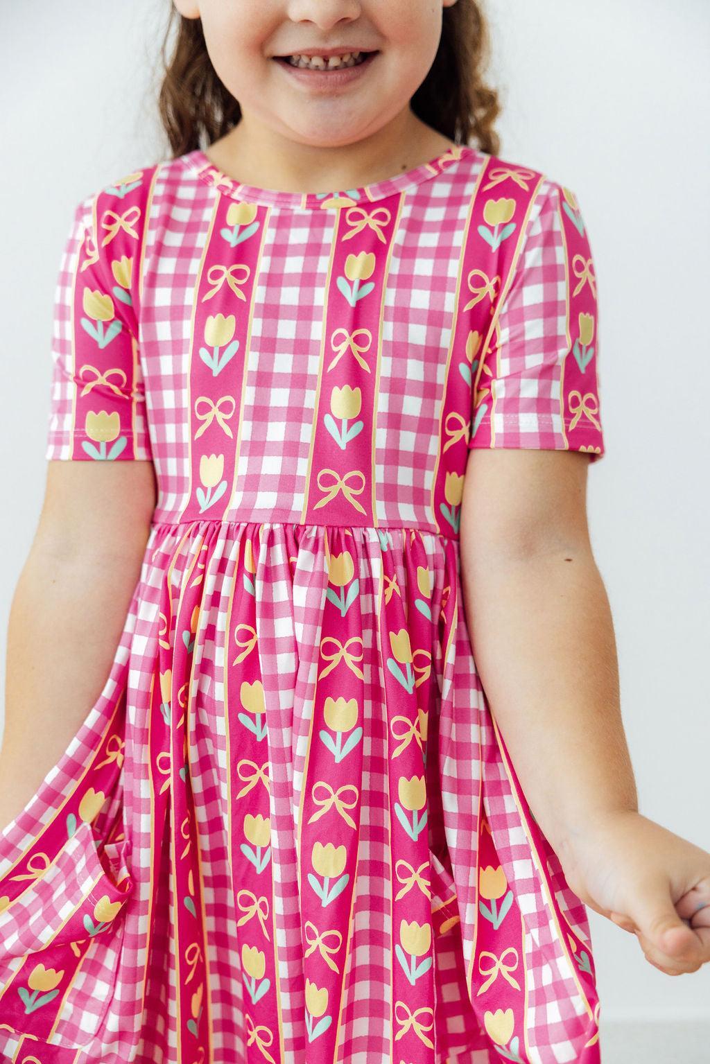 Girls pink plaid twirl dress with tulip and bow print, short sleeves, gathered skirt