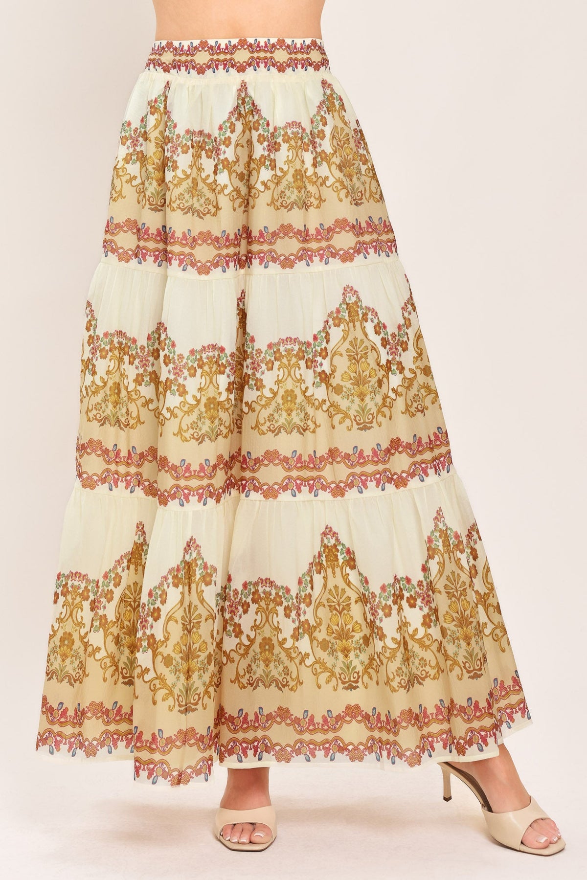 Ivory tiered maxi skirt with gold, orange-red, and green ornate print and ruffle tiers
