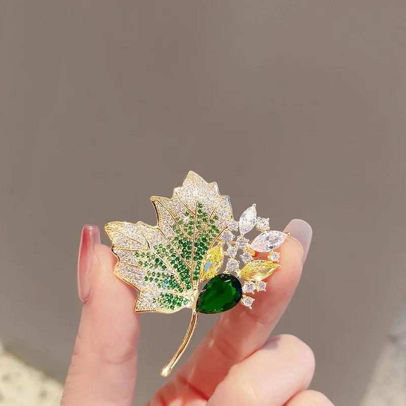 Gold-tone leaf brooch with green heart gem, orange and white crystal leaves, curved pin