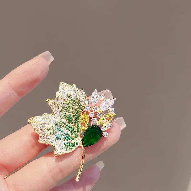 Gold-tone leaf brooch with green center gem, multicolor glitter leaves and dangling stones