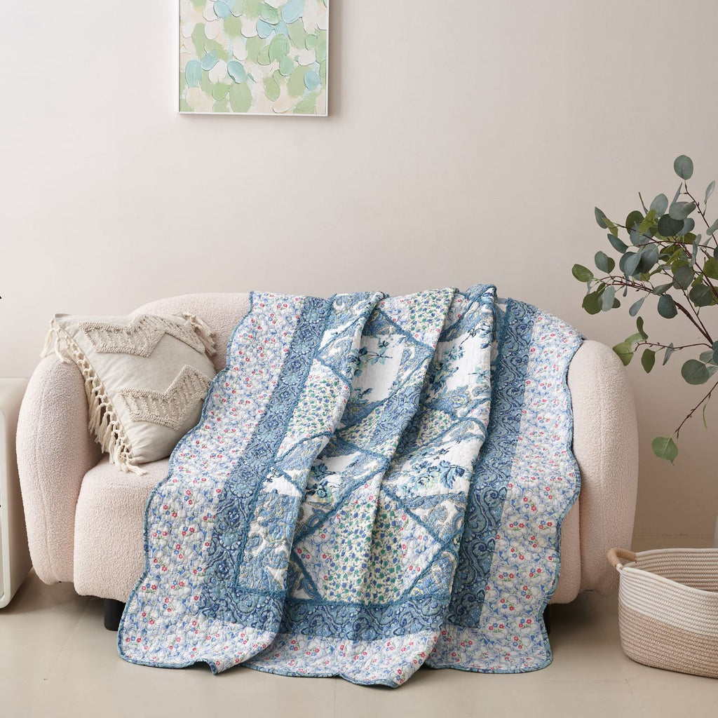 Blue and white floral patchwork quilt throw blanket draped over a sofa arm