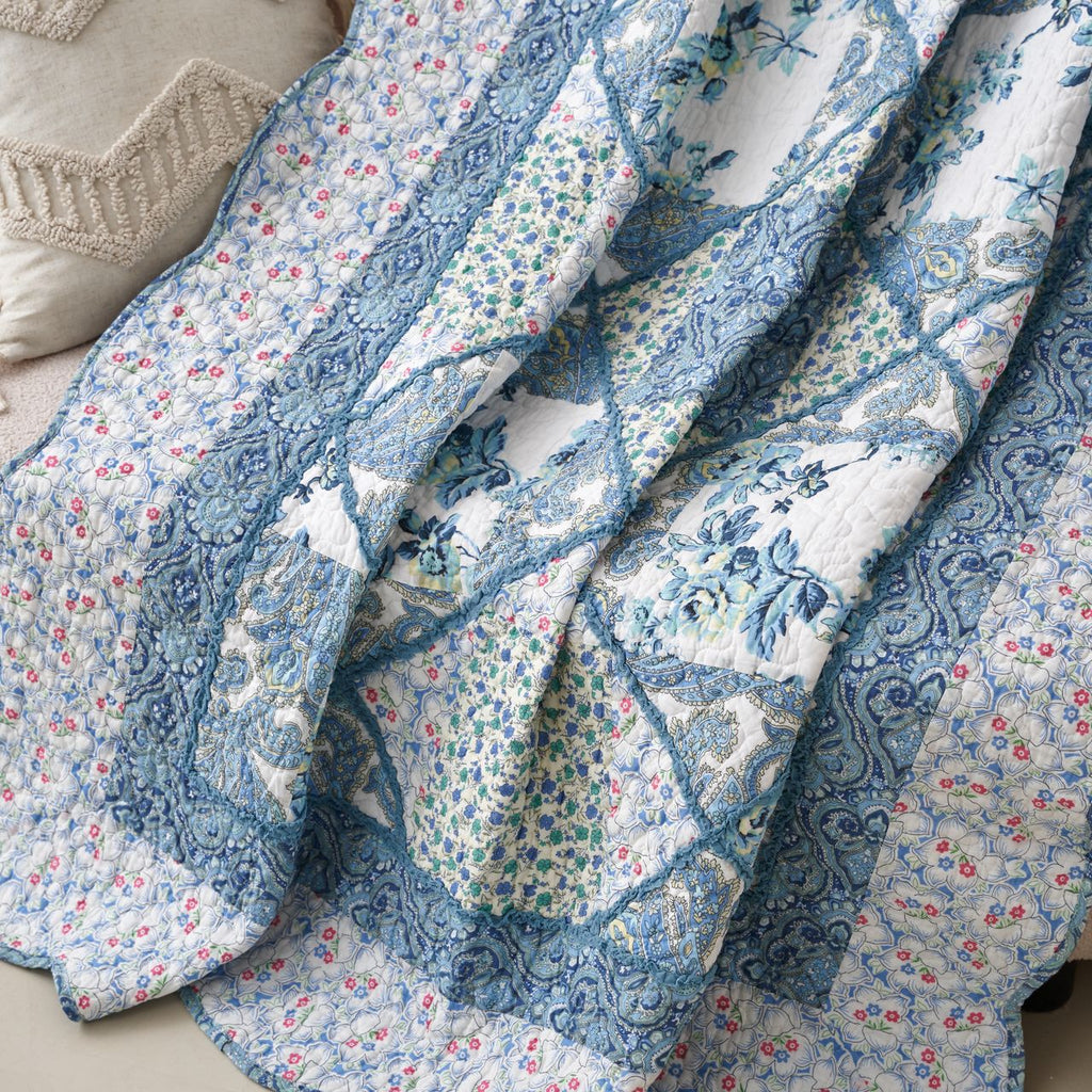 Overlapping view of blue and white floral patchwork quilt with stitched seams