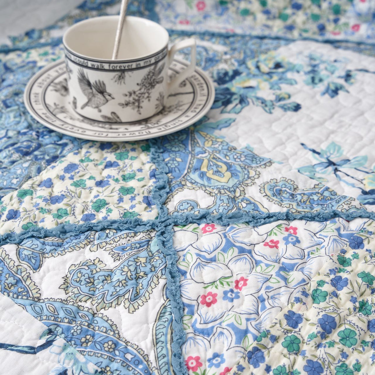 Close-up of blue-and-white floral patchwork quilt with stitched border and quilting