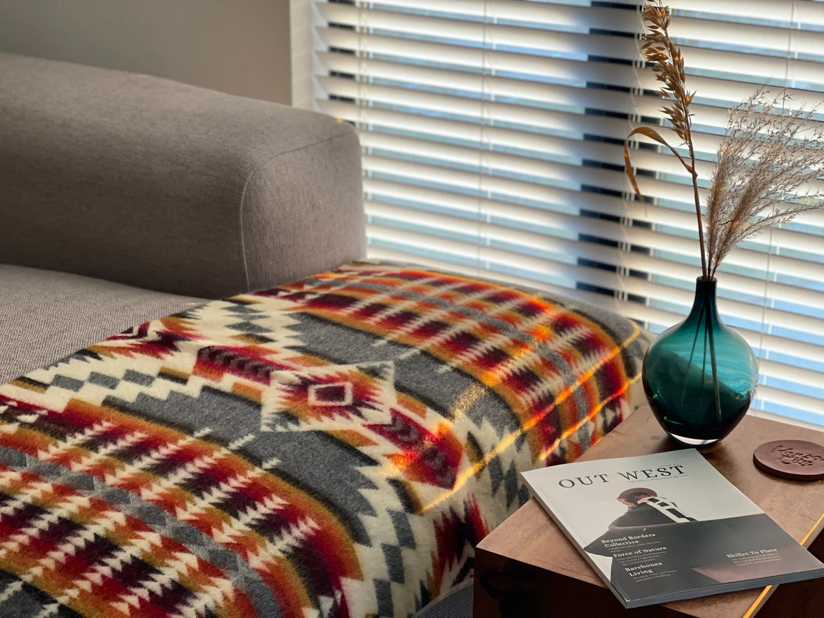 Geometric patterned throw blanket with multicolor accents draped on a sofa