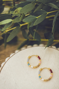 Gold-tone patchwork hoop earrings with blue and maroon bead-like segments