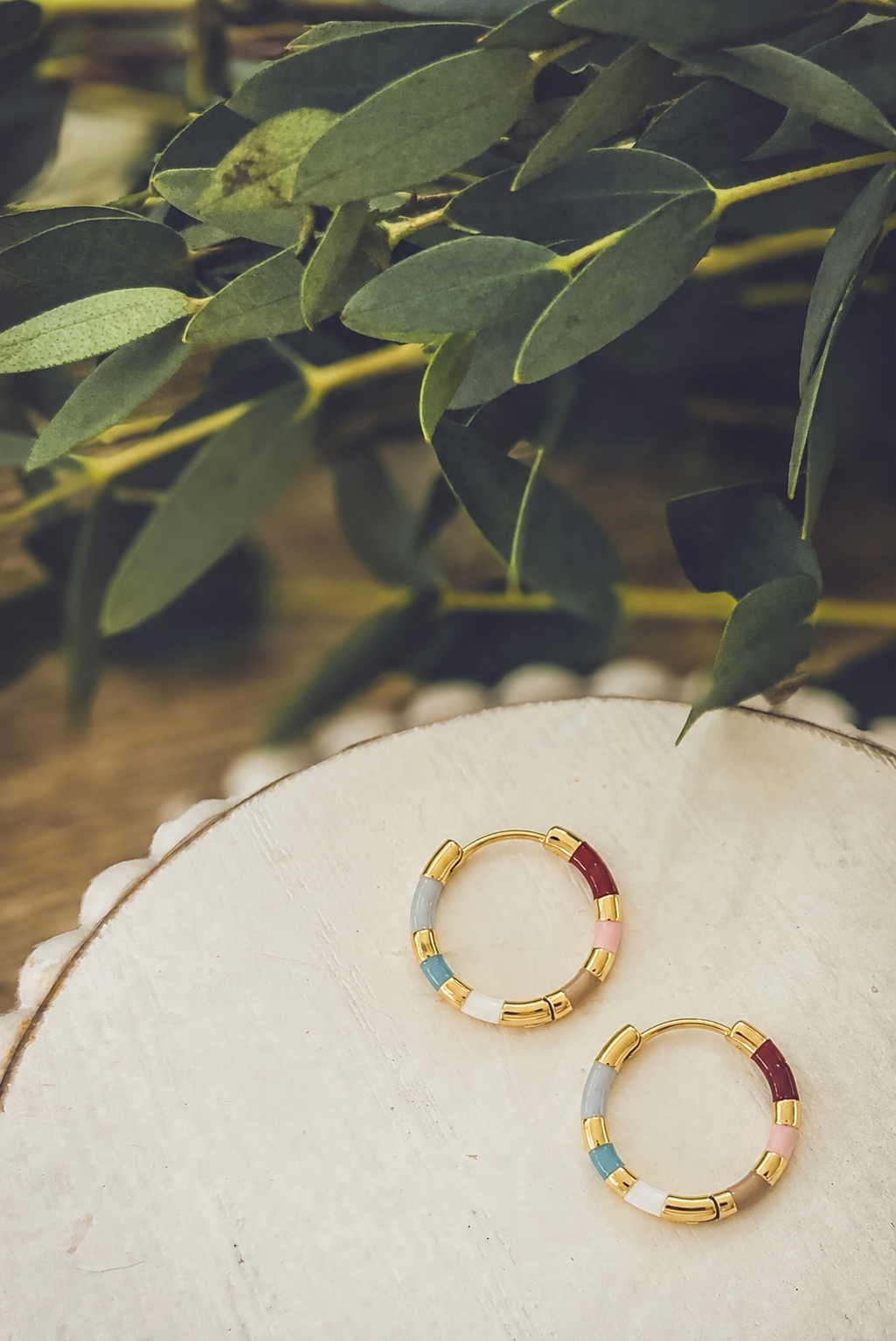 Gold-tone patchwork hoop earrings with blue and maroon bead-like segments