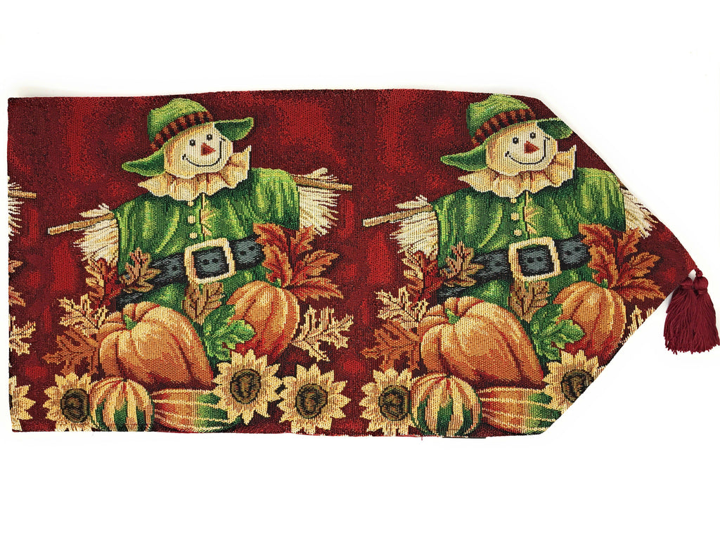 Red woven tapestry runner with scarecrow, pumpkins, and fringe tassel on edge.