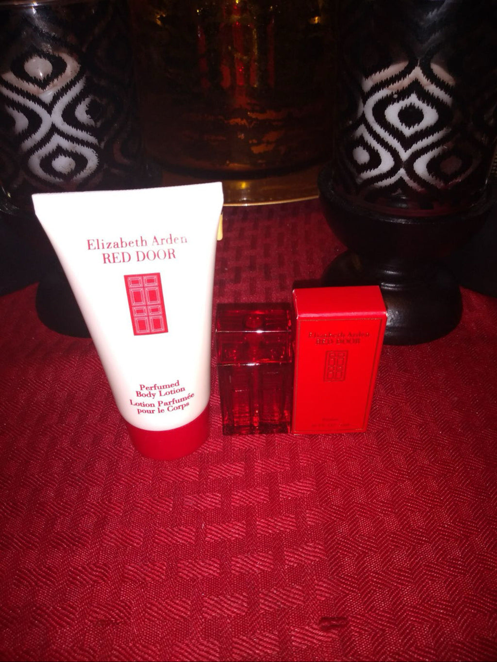Perfume set items: lotion tube, red bottle, and red box