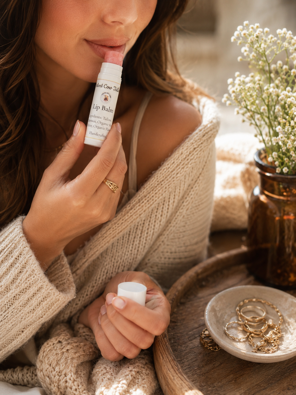 Lip balm stick tube in hand with cap, next to matching balm containers