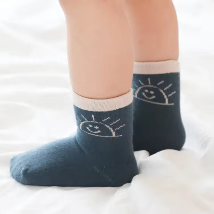 Toddler feet wearing dark navy socks with small sun face graphic