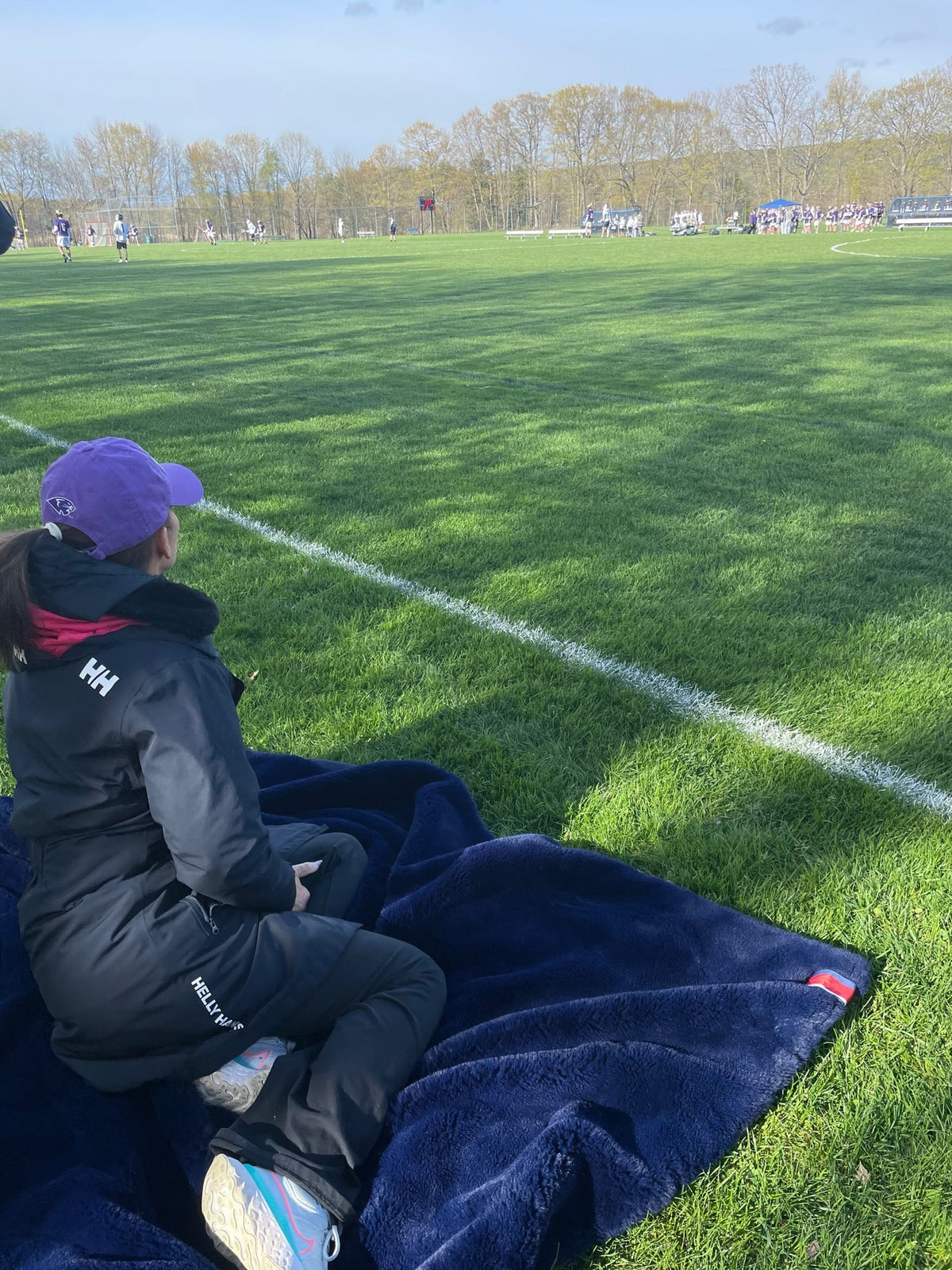 Navy outdoor blanket spread on grass at a sports field