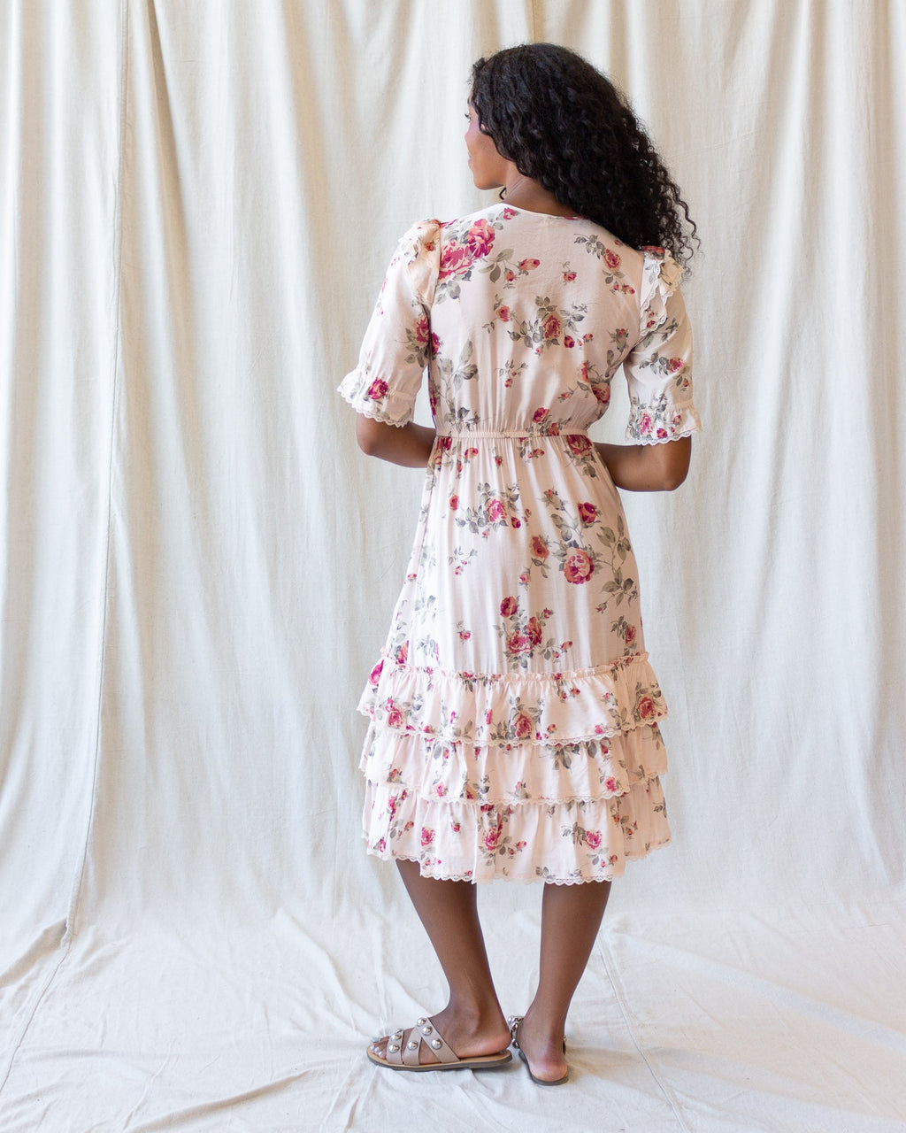 Back view of cream floral tiered mini dress with short puff sleeves and gathered ruffle layers