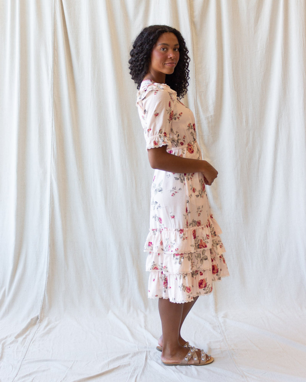 Side view of cream floral tiered mini dress with puff sleeves and ruffled tiers