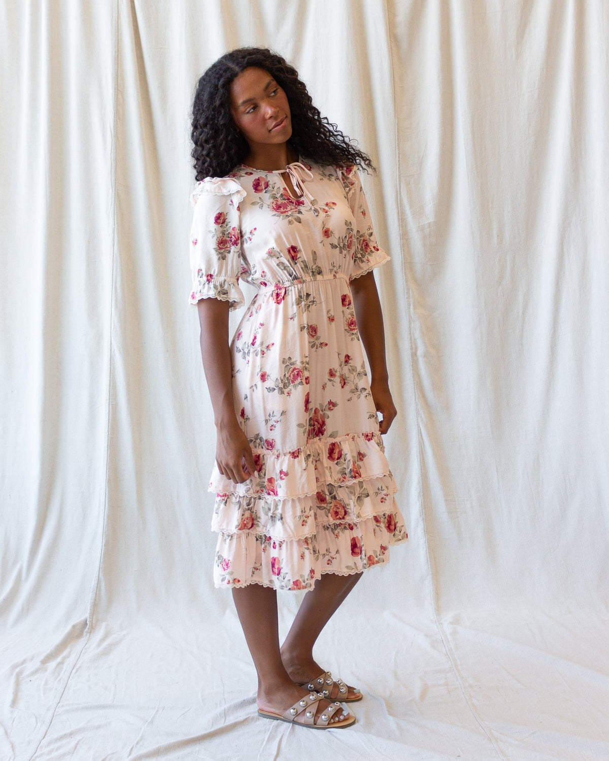 Full view of cream floral tiered mini dress with puff sleeves, ruffle tiers, and lace trim