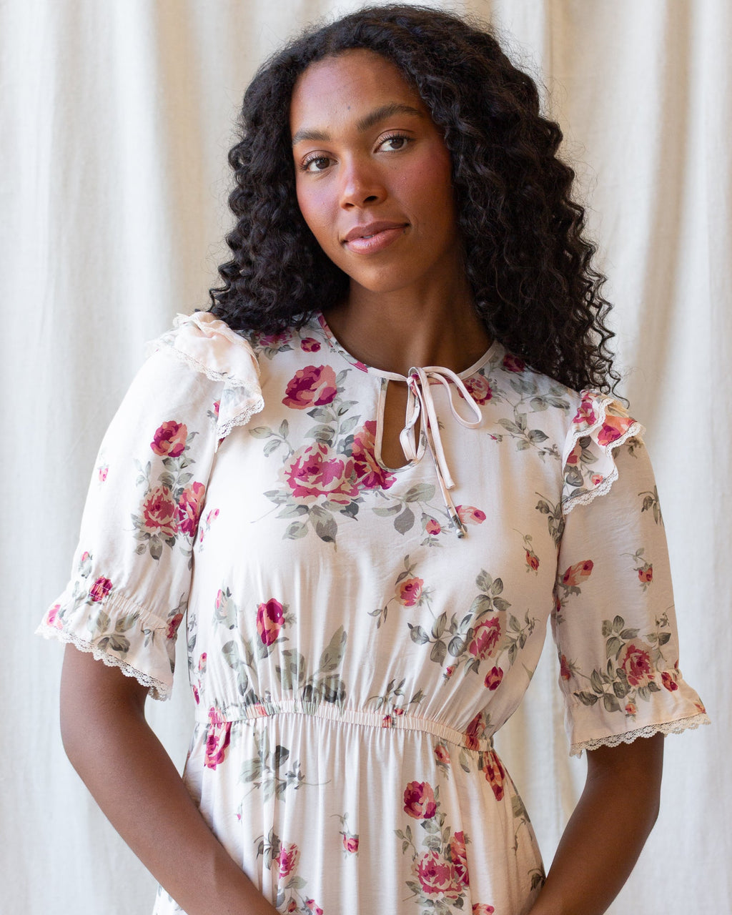 Close-up of cream floral dress with bow-tie neck and lace-trimmed puff sleeves
