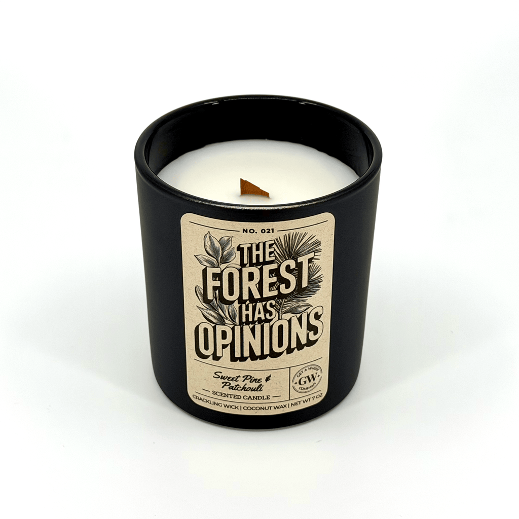 Black scented candle jar with white wax and “The Forest Has Opinions” label