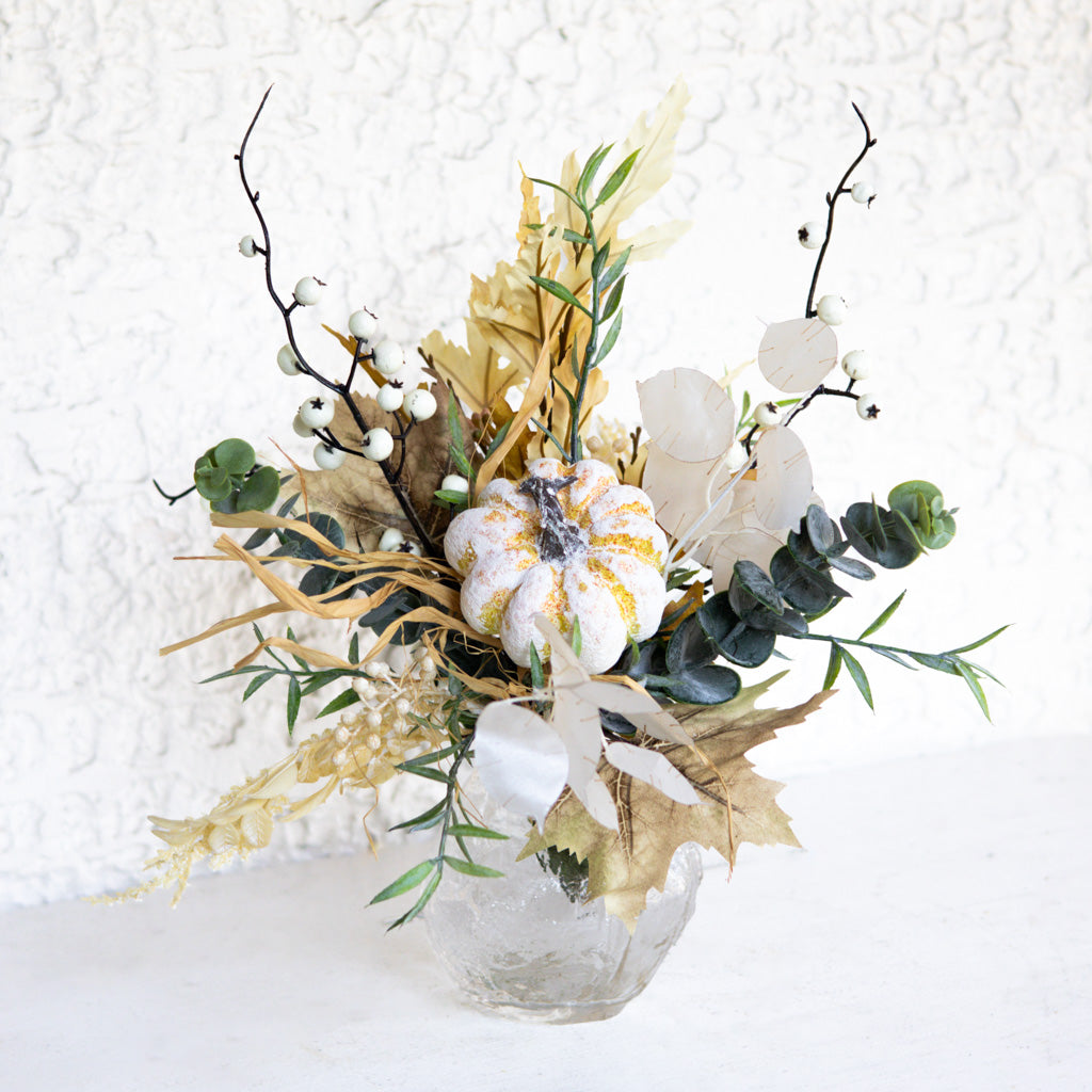 Floral bouquet in a ribbed vase with white-and-gold-speckled bloom, eucalyptus, and white leaf accents