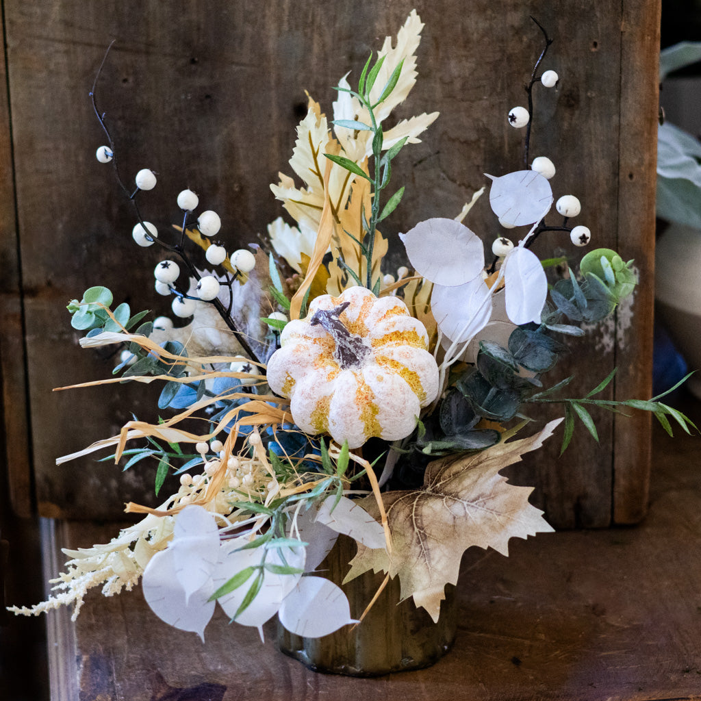 Floral arrangement in a ribbed vase with white blooms, gold specks, eucalyptus, and seed-like stems