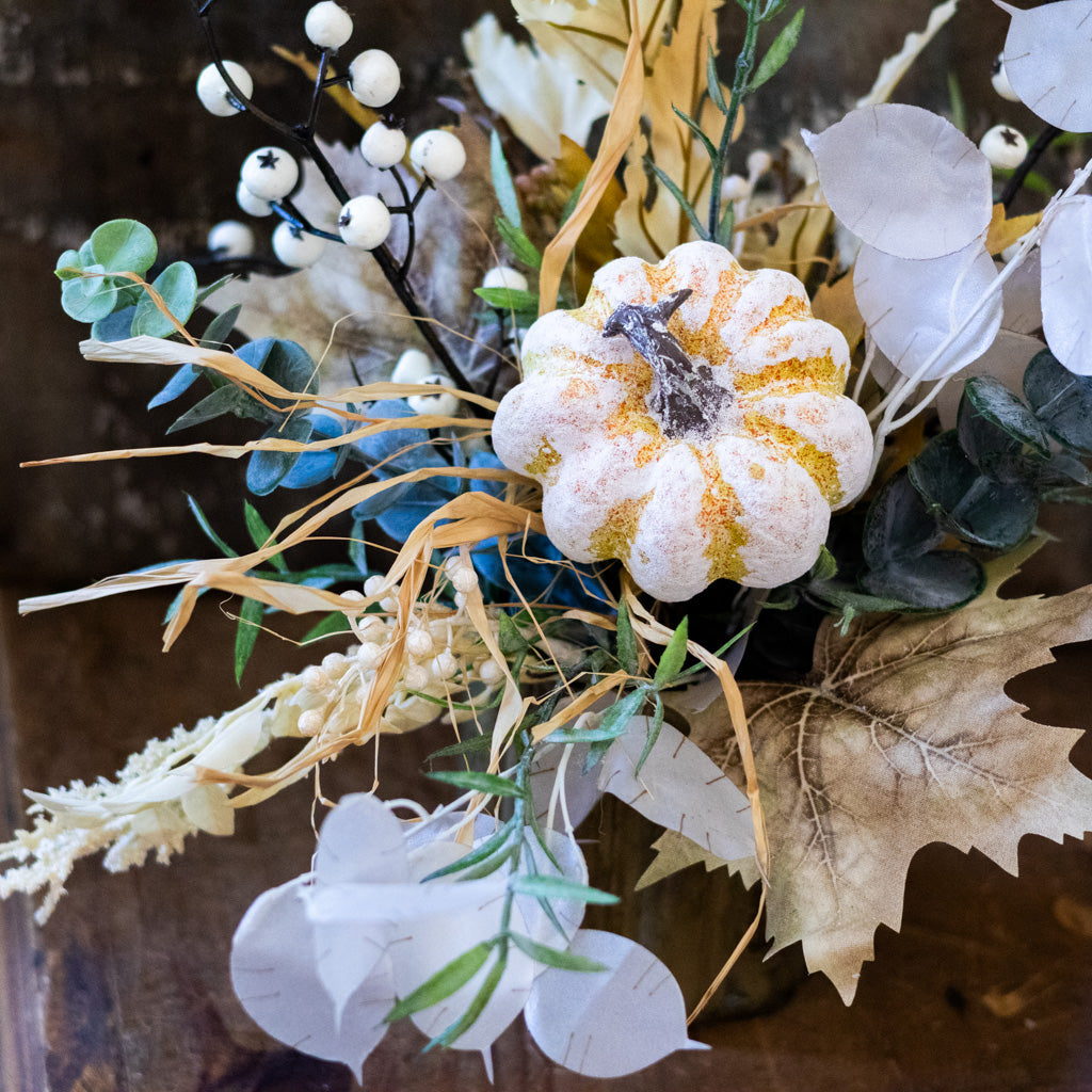 Close-up floral arrangement featuring a white gold-speckled bloom, eucalyptus, and white ball stems