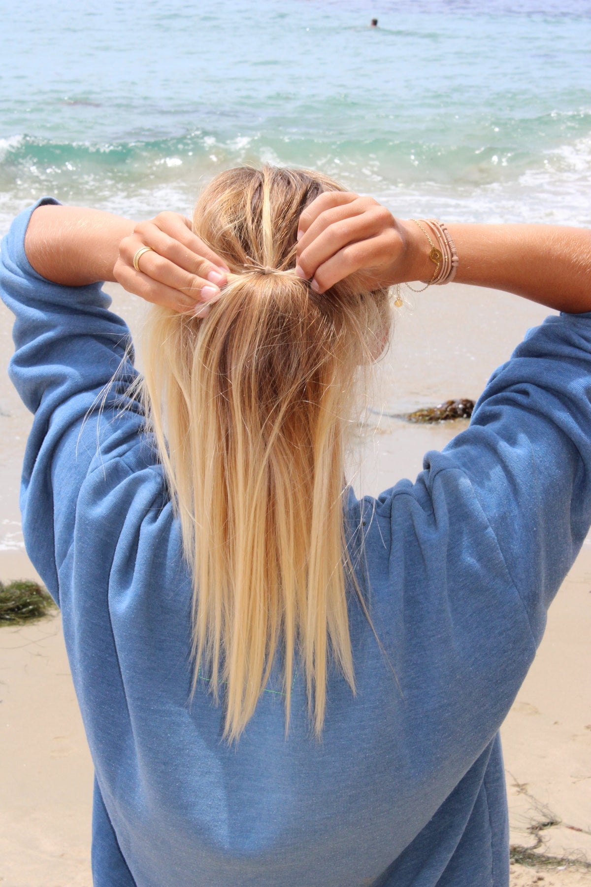 Long hair ponytail secured with a braided hair tie; bracelets on wrists