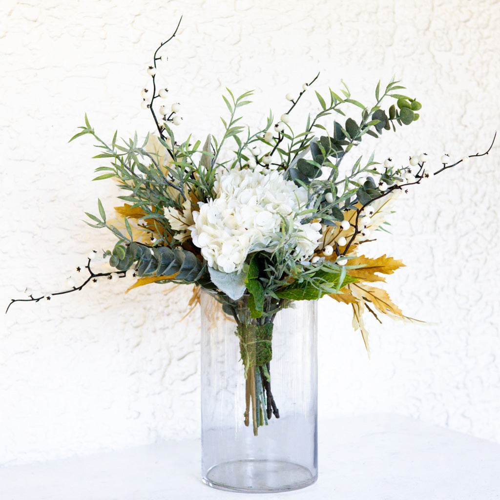 Floral bouquet in clear glass vase with white blooms, eucalyptus, and twig branches