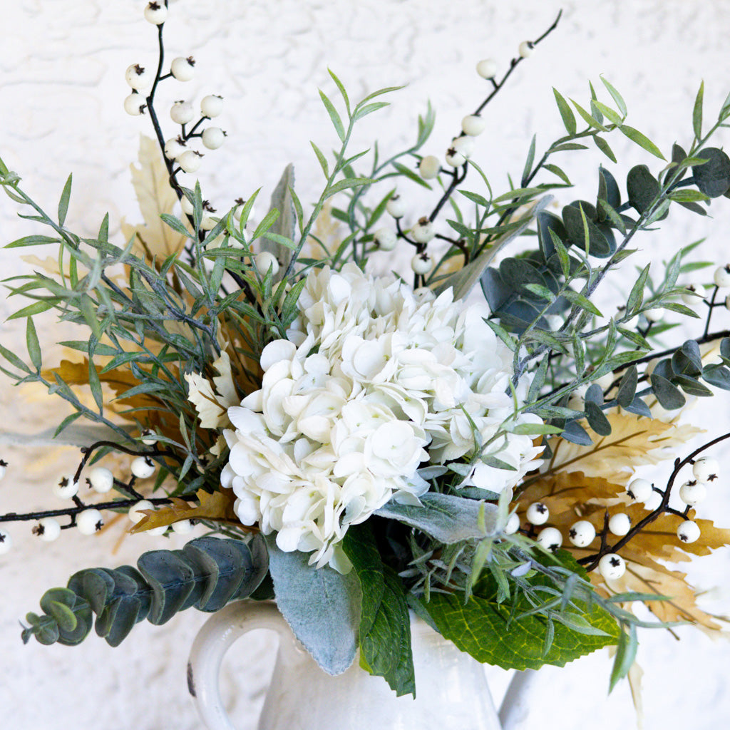 Floral bouquet with white cluster blooms, eucalyptus leaves, and small white berries in vase