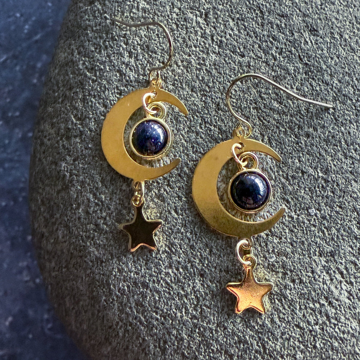 Gold crescent moon earrings with dark blue round stones and dangling star charms