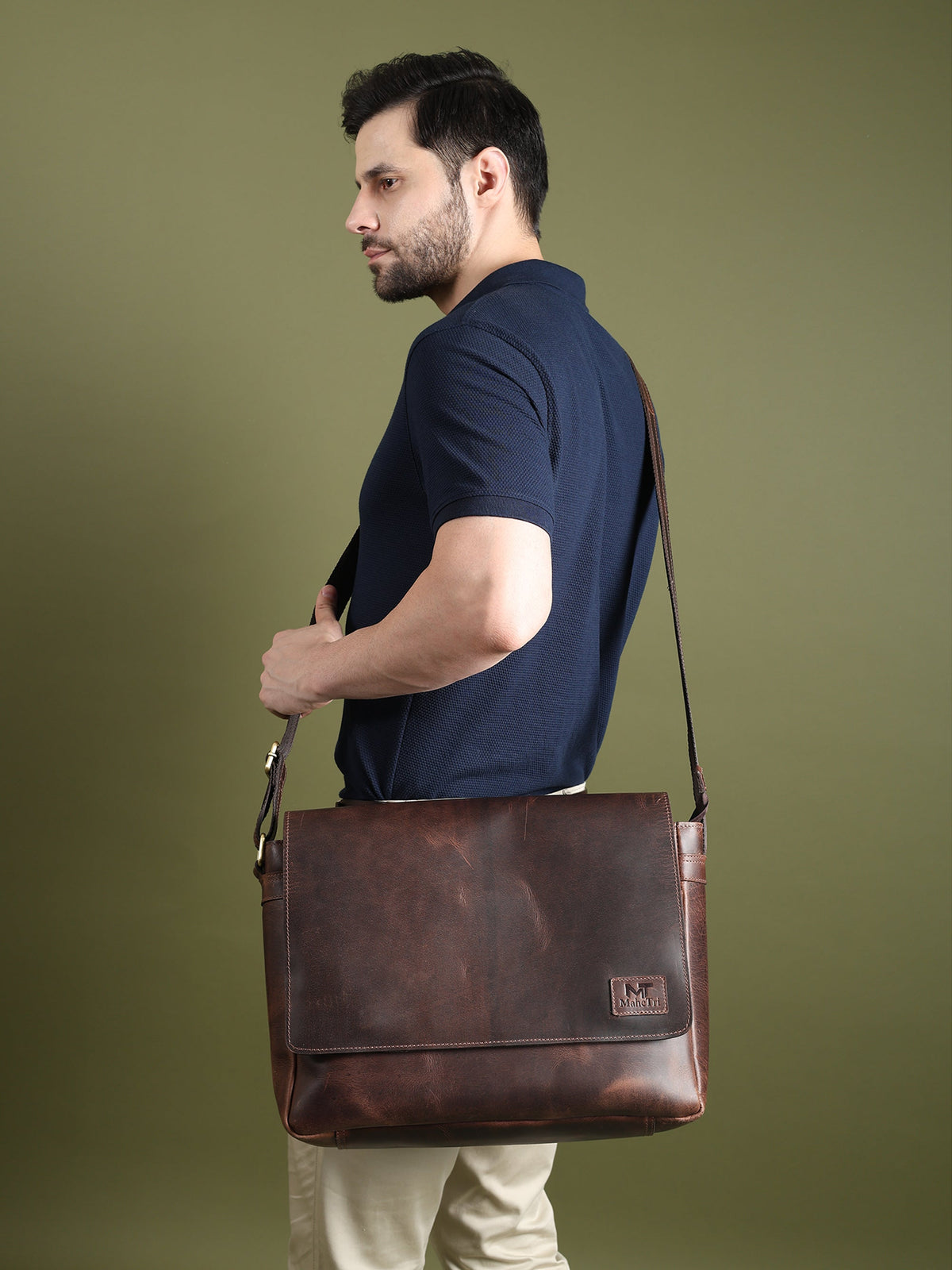 Genuine Sitka leather laptop bag shown from side while carried, dark brown with strap.